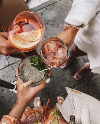 drei Personen stoßen mit Cocktails an, Blick von oben