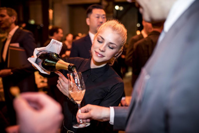 Servicekraft beim Ausschank von Sekt