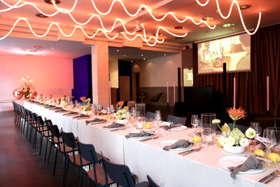 View into the GOOSE Eventspace hall with a reddish illuminated ceiling at event venue Frankfurt