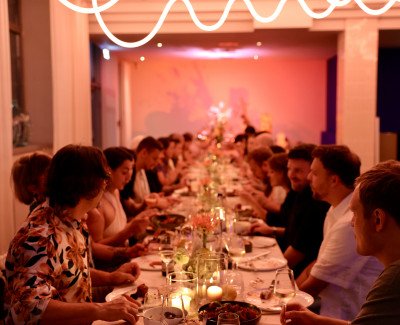 Menschen sitzen zu einem Dinner an einer langen Tafel zusammen